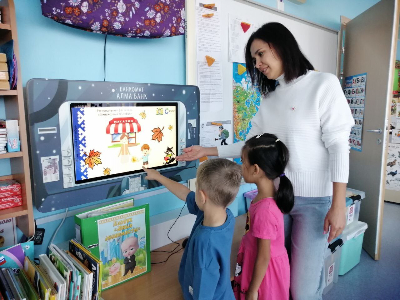 На фото два ребенка и воспитатель смотрят презентацию