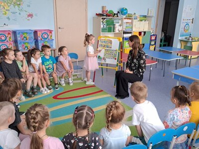 Дети сидят в кругу, воспитатель проводит занятие по ПДД, рассматривают иллюстрации