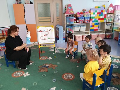 На фото воспитатель с игрушкой-зайцем в руках проводит тематическое занятие по ПДД