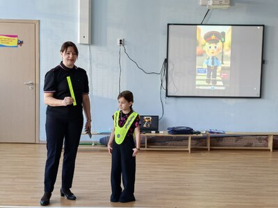 Девочка в светоотражающем жилете, инспектор со светоотображающим браслетом