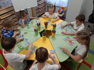 На фото дети выполняют за столом  задания в рабочих тетрадях по дополнительной программе На пороге школы